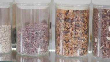 Farklı taneler ve tohumlar bir raftaki açık kaplarda sergilenir..
