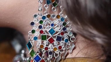 Bu klipte, canlı taşlar ve metal işçiliğinden oluşan karmaşık küpeler sergileniyor..