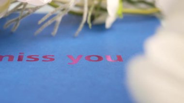 İçten bir mesajı olan bir kart çiçeklerle çevrilidir, sevgiyi gösterir..