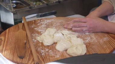 Ustaca yoğurup hamuru un ahşap bir tahtanın üzerinde şekillendirir..