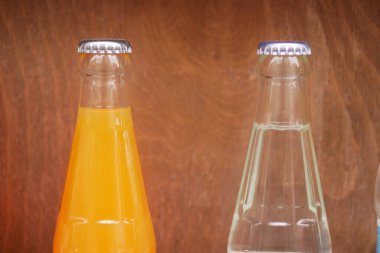 Portakal ve temiz içeceklerle dolu iki cam şişe yan yana oturur..