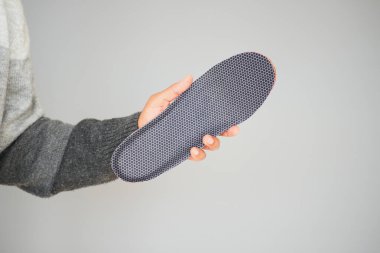 Bir insan hafif arka planda kumaş ve lastik ayakkabı tutar..