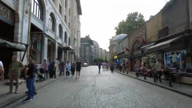 Alışveriş yapan ve atmosferin tadını çıkaran insanlarla dolu hareketli bir cadde..