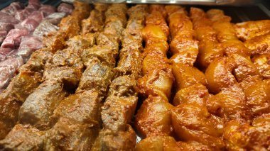Salamuraya yatırılmış çeşitli şiş etler ve bir barbekü partisinde ızgara..