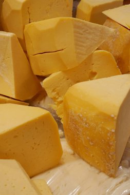 Bir markette düzenli olarak satılmak üzere düzenlenmiş çeşitli sarı peynir parçaları..