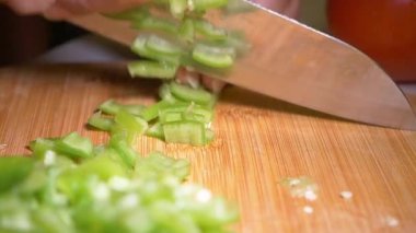 Tahta kesme tahtasındaki yeşil dolma biberi ustalıkla kesiyor..