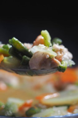 Renkli kızarmış sebzeler ve tavuk bir kaşıkta sergilenir..