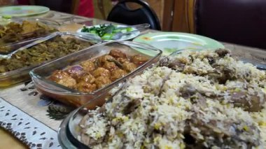 Aile üyeleri çeşitli geleneksel yemeklerden oluşan bir yemeği paylaşıyorlar..