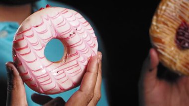 İki el lezzetli çörekler tutar canlı renkler ve krema sergiler..