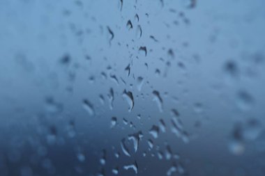 Yağmur damlaları pencereye yapışır, yağmurlu bir günde dış görünüşü bulanıklaştırır..