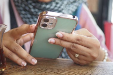 Kafedeki akıllı telefonuna odaklanmış bir kadın çayından zevk alır..