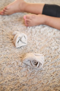 Bir çocuk yumuşak bir halıya sarılmış çoraplarla rahatlar..