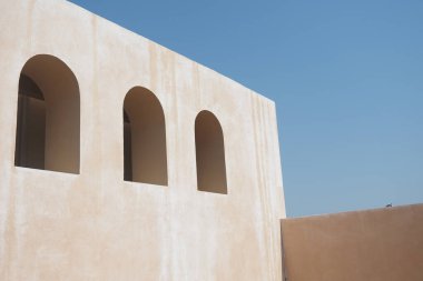 Parlak yapı, berrak bir gökyüzüne karşı dizilmiş yuvarlak kemerlere sahiptir.