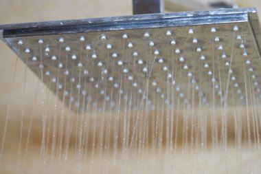 Parlak bir banyodaki parlak bir duş başlığından çağlayarak akan sular..