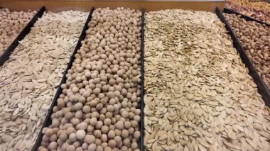Pazarda tepsilerde sergilenen çeşitli tohumlar ve fındıklar keşfedin..