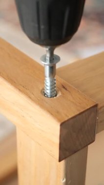 Tahta mobilya parçalarını güvenli bir şekilde birleştirmek için elektrikli matkap kullanılıyor..