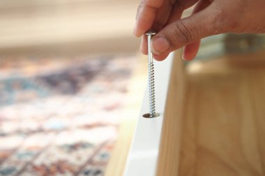 El dikkatle montaj için tahta mobilyalara vida yerleştirir.