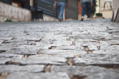 İnsanlar şehirde sessiz, dar bir kaldırım taşı caddesinde geziniyor..