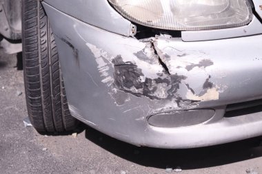 Hasarlı bir araba yol kenarında oturur derin çizikler ve göçüklerle.