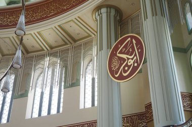 Dekoratif sütunların ve hat sanatının yer aldığı zarif bir cami iç mimarisi..