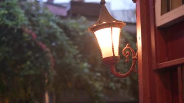 Süslü bir fenerin yumuşak ışığı dışarıda sıcak bir atmosfer yaratır..