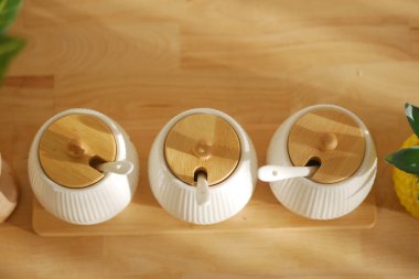 Ahşap kapaklı üç seramik kap bir mutfaktaki ahşap tepside oturur..