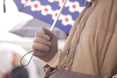 Yağmurda yol alırken sıcak tutan bir kişi şemsiye tutar..