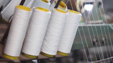 Üretimi gösteren bir tekstil fabrikasında beyaz iplik makaralarının görüntüsü.