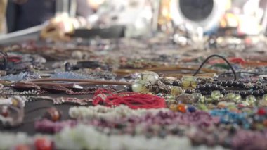 Yoğun bir gündüz pazarında renkli el yapımı mücevherler parlıyor.