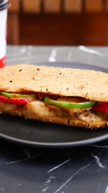 Renkli sebzeler ve susamlı ekmek aromalı lezzetli bir sandviçin tadını çıkarın..