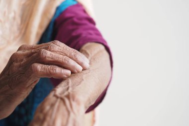 Yaşlı eller sakin bir ortamda deri dokusunu dikkatle inceler..