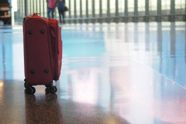 Havaalanından geçen yolcuların geçtiği yerde kırmızı bir bavul duruyor..