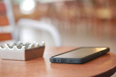 Kafedeki boş bir kül tablasının yanına yerleştirilmiş akıllı telefon..