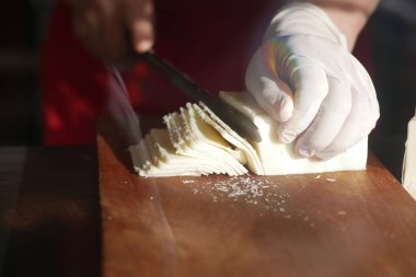 Bir satıcı, pazarda tahtadan taze peynir kesiyor..