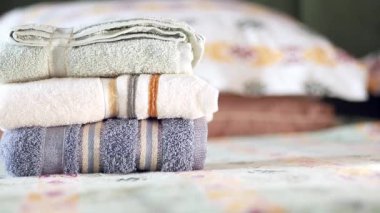 Yumuşak havlular, sıcak bir odada renkli yatakların yanına güzelce istiflenir..