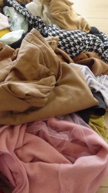 Bir kişi çeşitli giysi parçalarını parlak renklere ve dokulara göre düzenler.