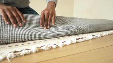 Bir insan dekorasyon için ahşap zemine şık bir halı serer..