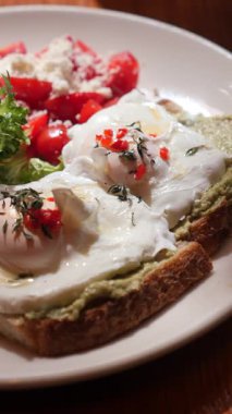 Haşlanmış yumurta, avokado sosu ve salata içeren lezzetli bir yemeğin tadını çıkarıyorum..