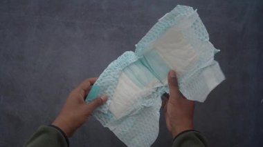 Bebek bezi tutan bir elin en üst görüntüsü.