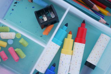 Kalemler, kalemler ve keskinleştirici bir el işi kutusuna yerleştirilmiş..