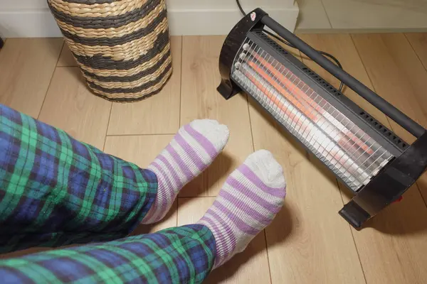 Isınmak için ısıtıcı tarafından yerleştirilmiş çizgili çorapların içinde rahat ayaklar..