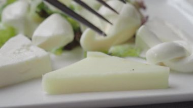 Taze peynir dilimleri canlı salata yeşilliklerinden oluşan bir yatakta servis edilir..