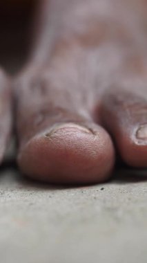 Sıska ayak parmakları kaba bir yüzeyde dinleniyor, günlük hayattan kalma gösterişli giysiler..