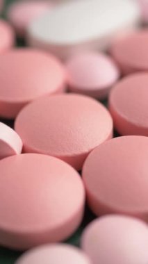 Yeşil bir yüzey üzerinde sergilenen pembe ve beyaz yuvarlak tablet koleksiyonu.