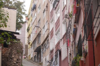 İnsanlar canlı binalarla çevrili kaldırımlı bir cadde boyunca yürürler..