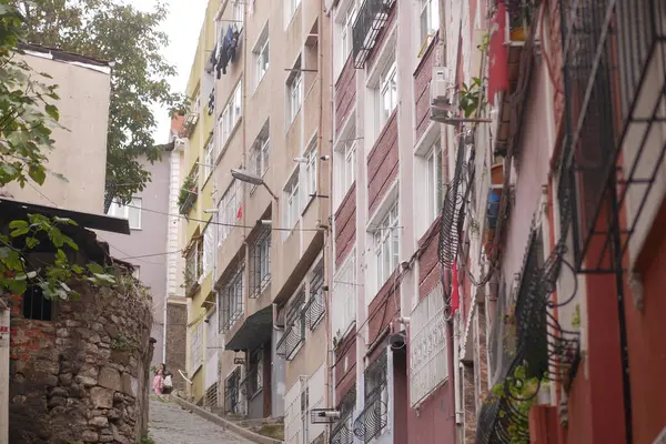 İnsanlar canlı binalarla çevrili kaldırımlı bir cadde boyunca yürürler..