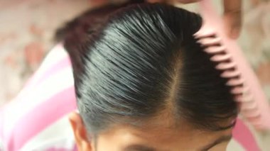 Genç bir insan saçlarını parlak bir görünüş için tarar..