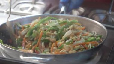 Sıcak tavada rengarenk sebze ve tavuk karışımı karıştırmak..