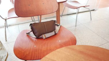 Kahverengi çanta bir kafede tahta bir sandalyede..