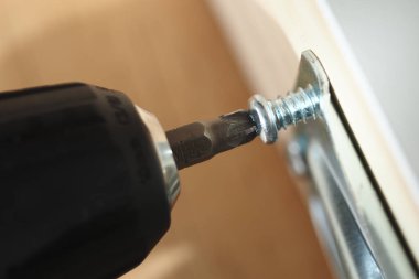 Tahta bir yüzeye vida yerleştirmek için matkap kullanılıyor..